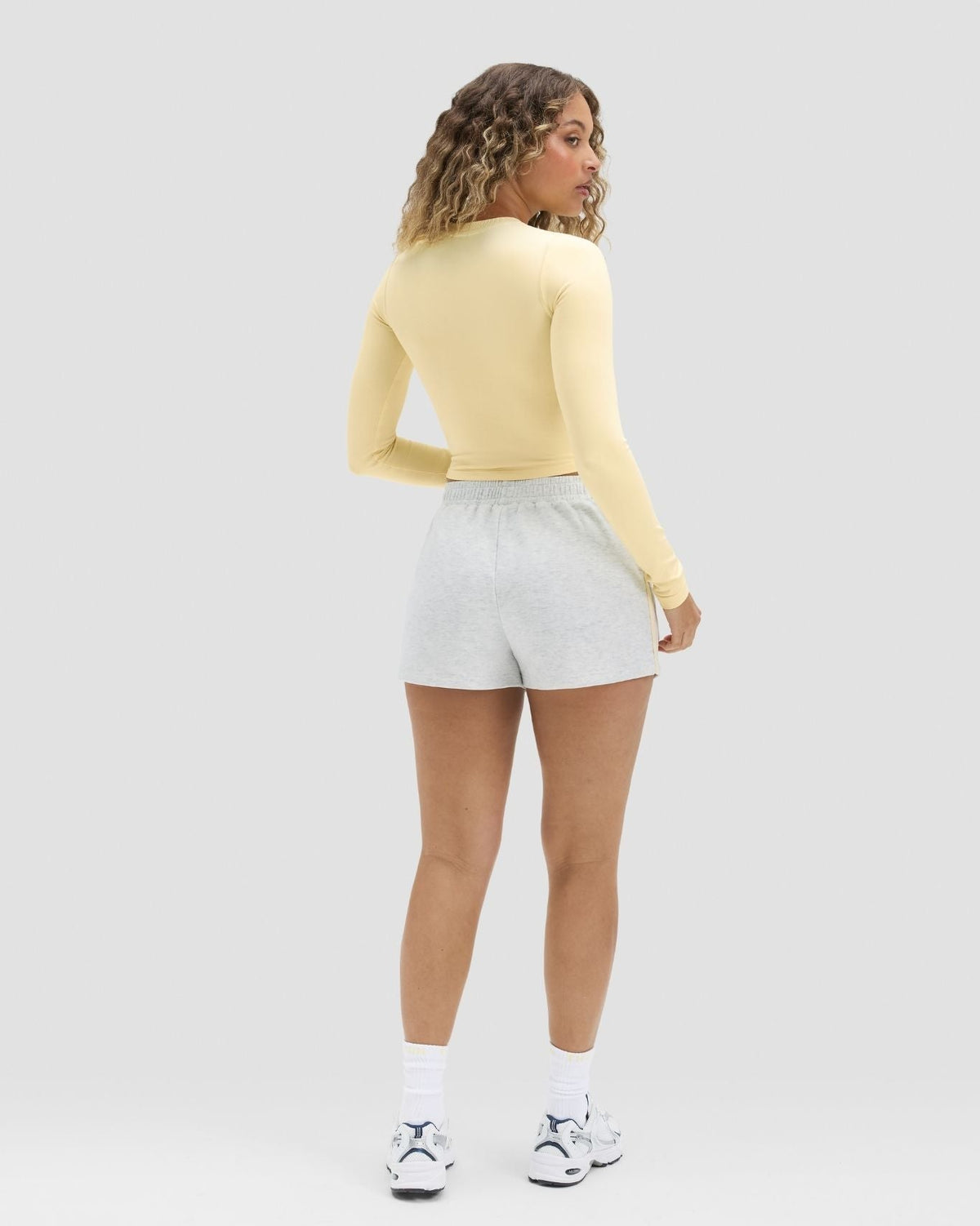 Elevate Compression Long Sleeve Top in Butter Yellow, back view with grey shorts
