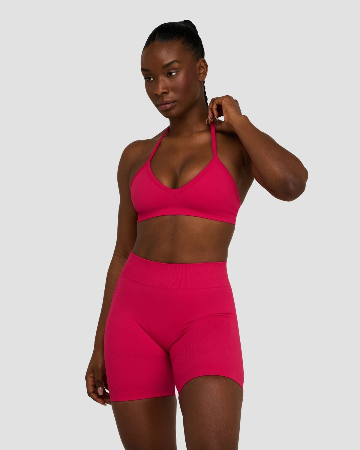 Elevate Sculpting Seamless Adjustable Halter Bra in Strawberry, front view with hand at neck, styled with matching shorts