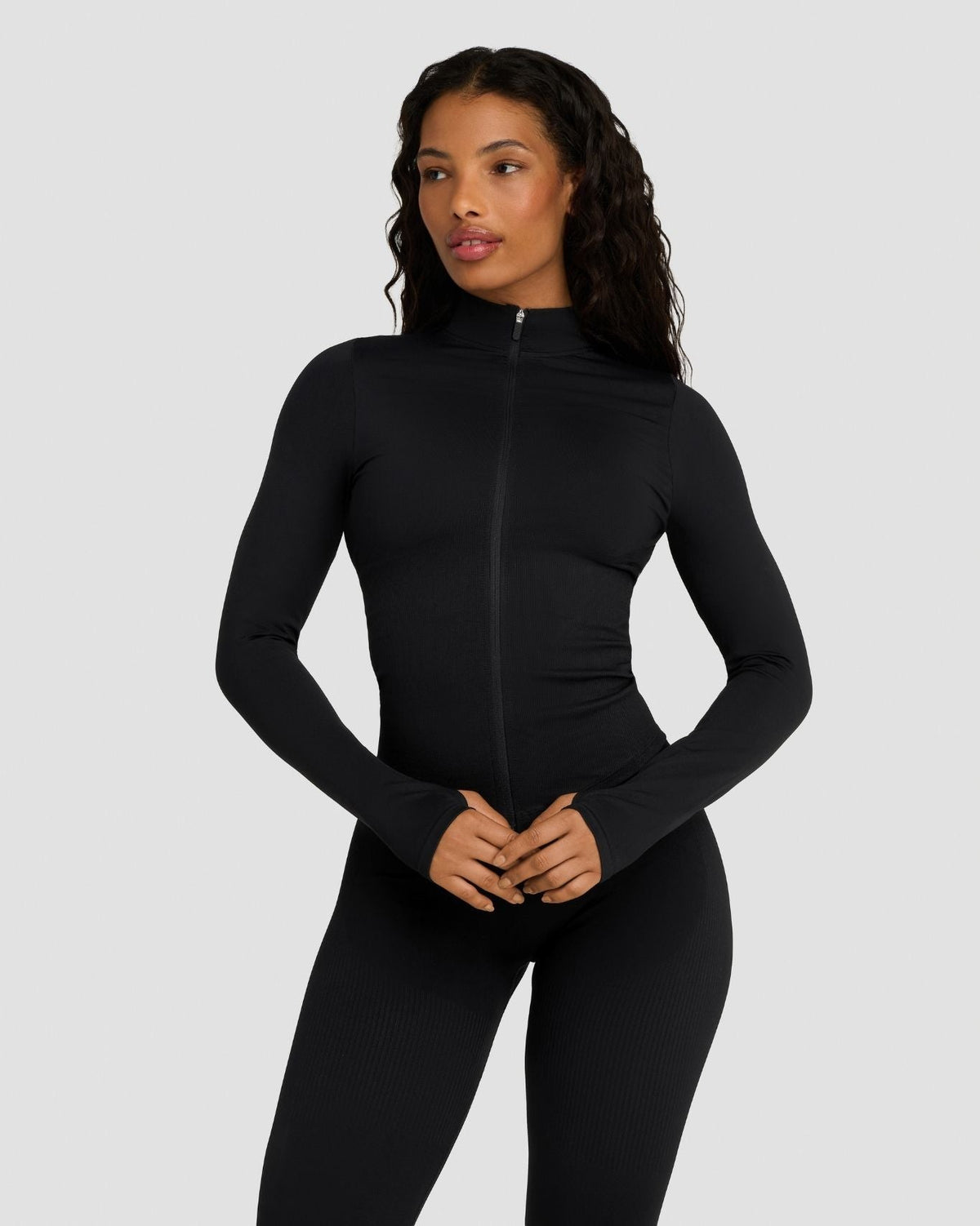 Elevate Compression Long Sleeve Jacket in Night Black, front view zipped up, hands clasped at waist