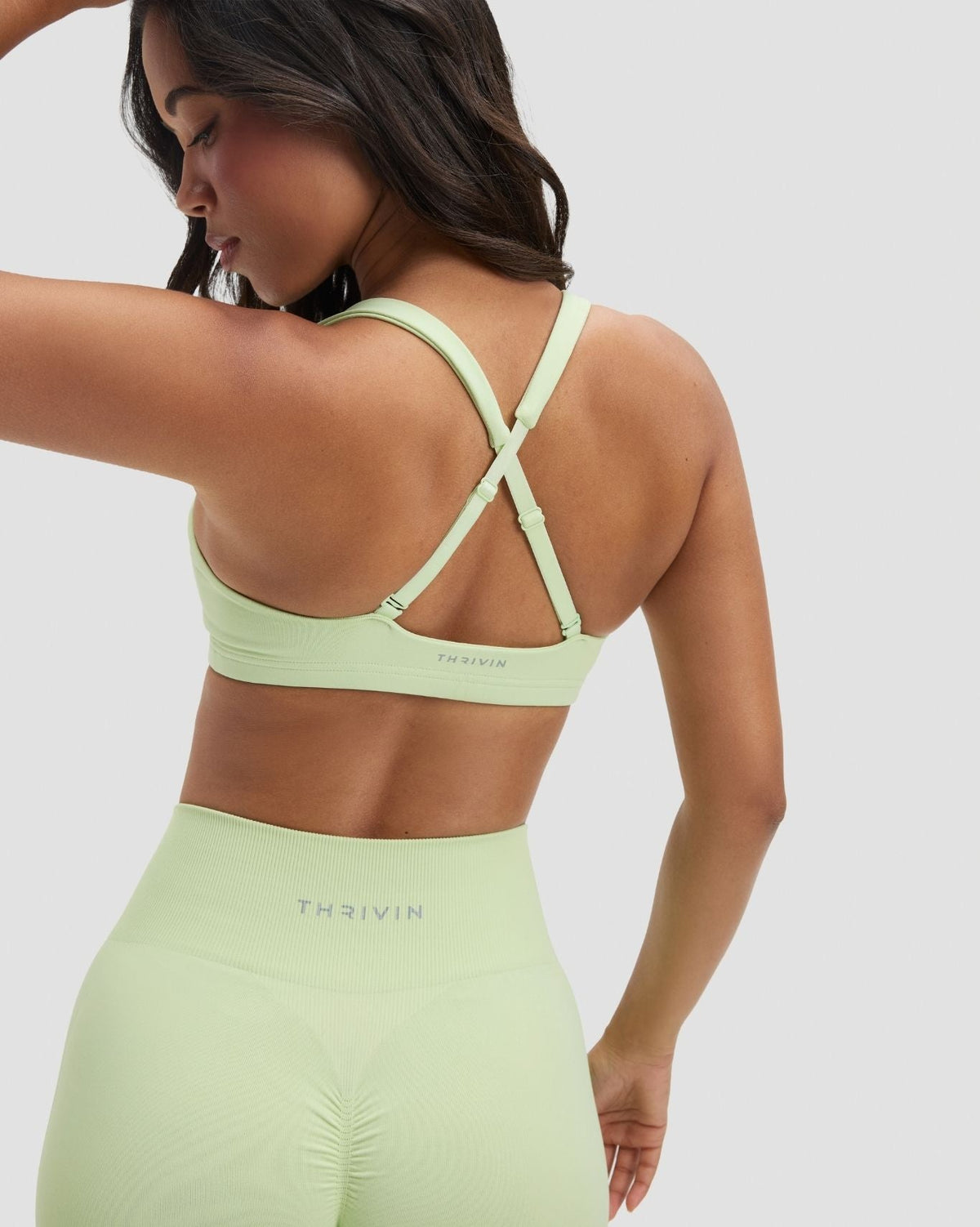 Elevate Sculpting Medium Impact Multiway Bra in Pistachio Green, back view of criss-cross straps styled with leggings