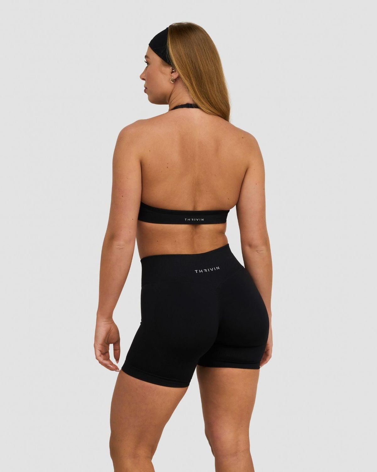 Elevate Sculpting Seamless Adjustable Halter Bra in Night Black, back view with halter ties and band, styled with shorts