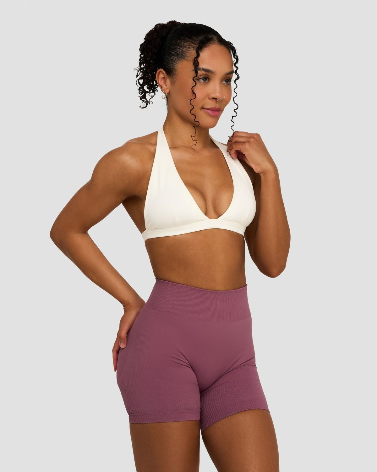 Elevate Sculpting Seamless V-Neck Halter Bra in Cream, front view with hand on hip, styled with shorts