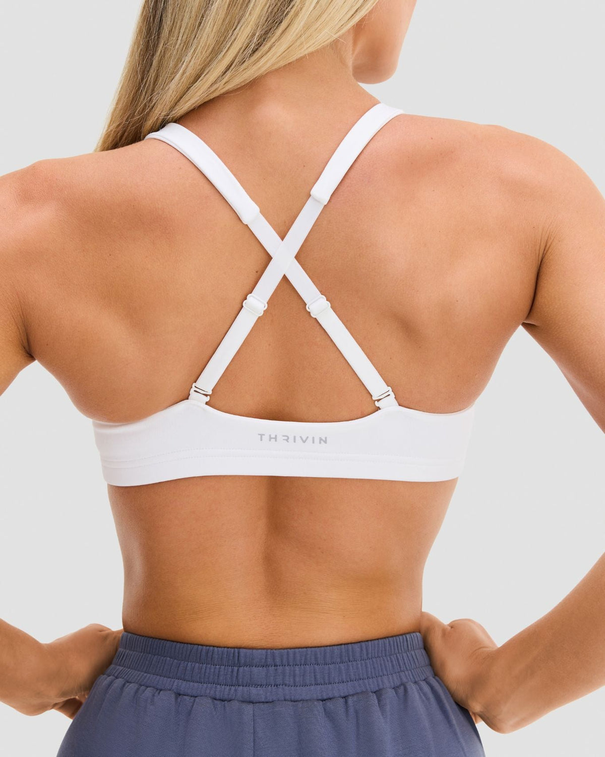 Elevate Sculpting Medium Impact Multiway Bra in White, back close-up of crossed straps, adjustable sliders and THRIVIN logo