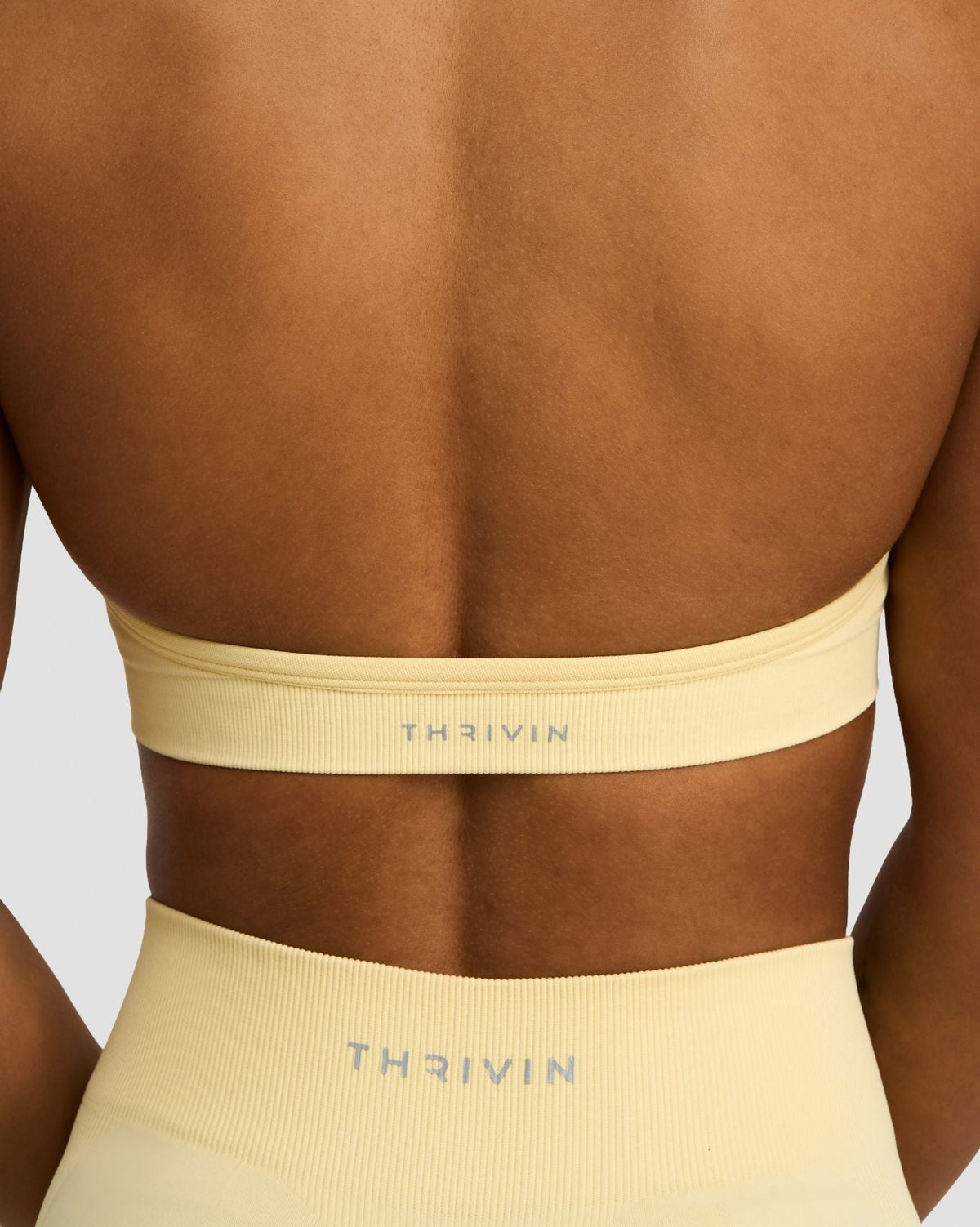 Elevate Sculpting Seamless Adjustable Halter Bra in Butter Yellow, back close-up of band with THRIVIN logo