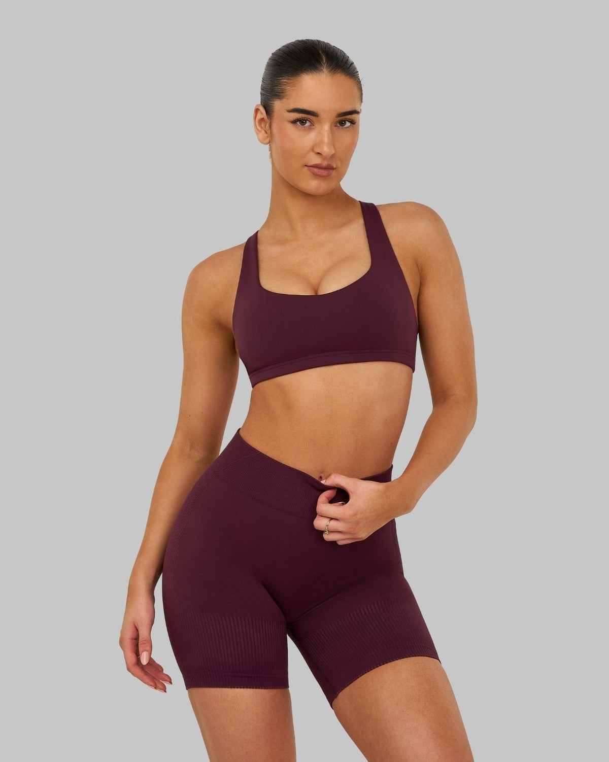 Elevate Sculpting Medium Impact Multiway Bra in Winter Plum Red, front view styled with shorts, hand on waist
