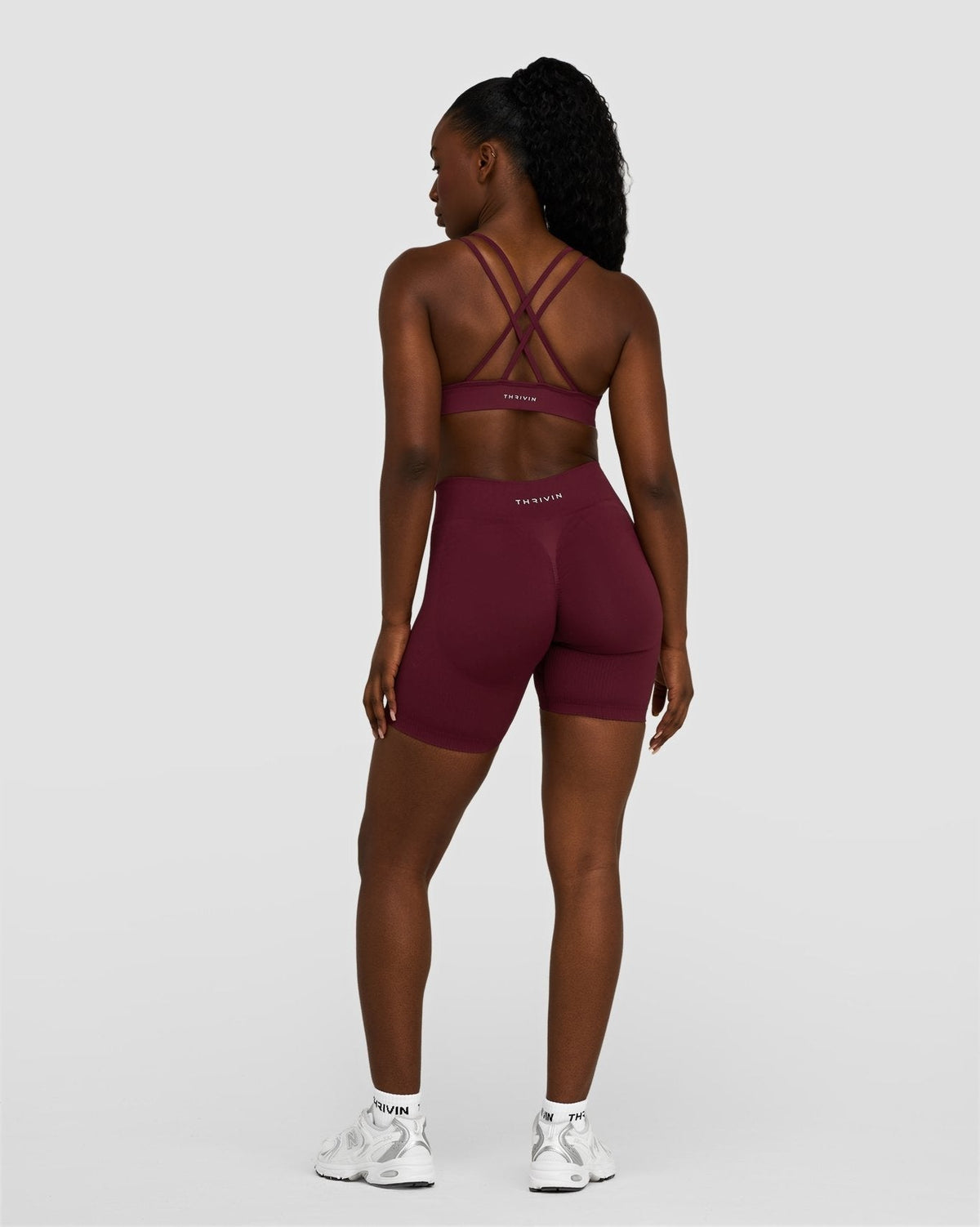 Elevate Sculpting Mid Waist Scrunch Shorts in Merlot, back view with strappy bra
