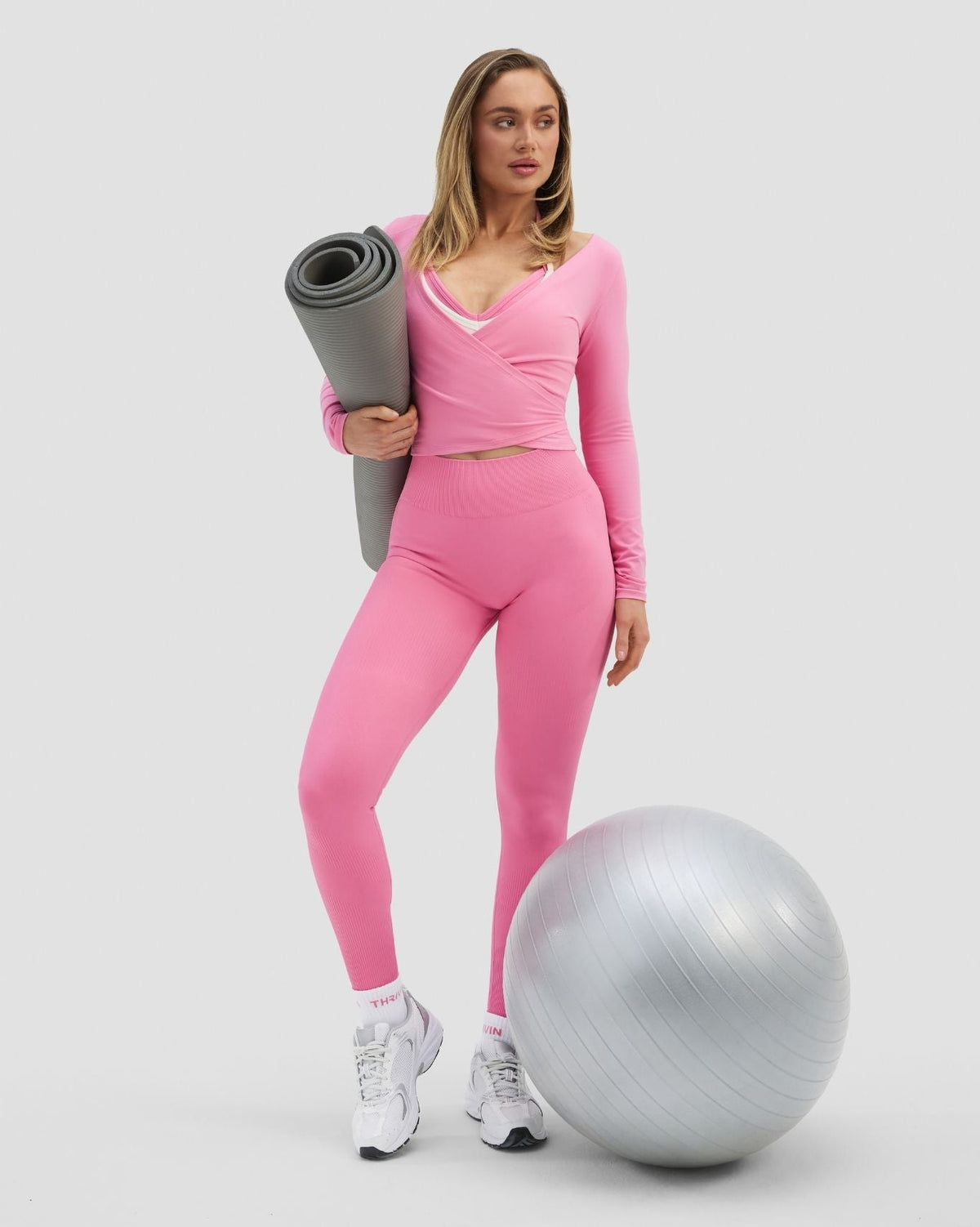 Elevate Sculpting Seamless Adjustable Halter Bra in Bubble Pink, full-length front view with yoga mat and exercise ball
