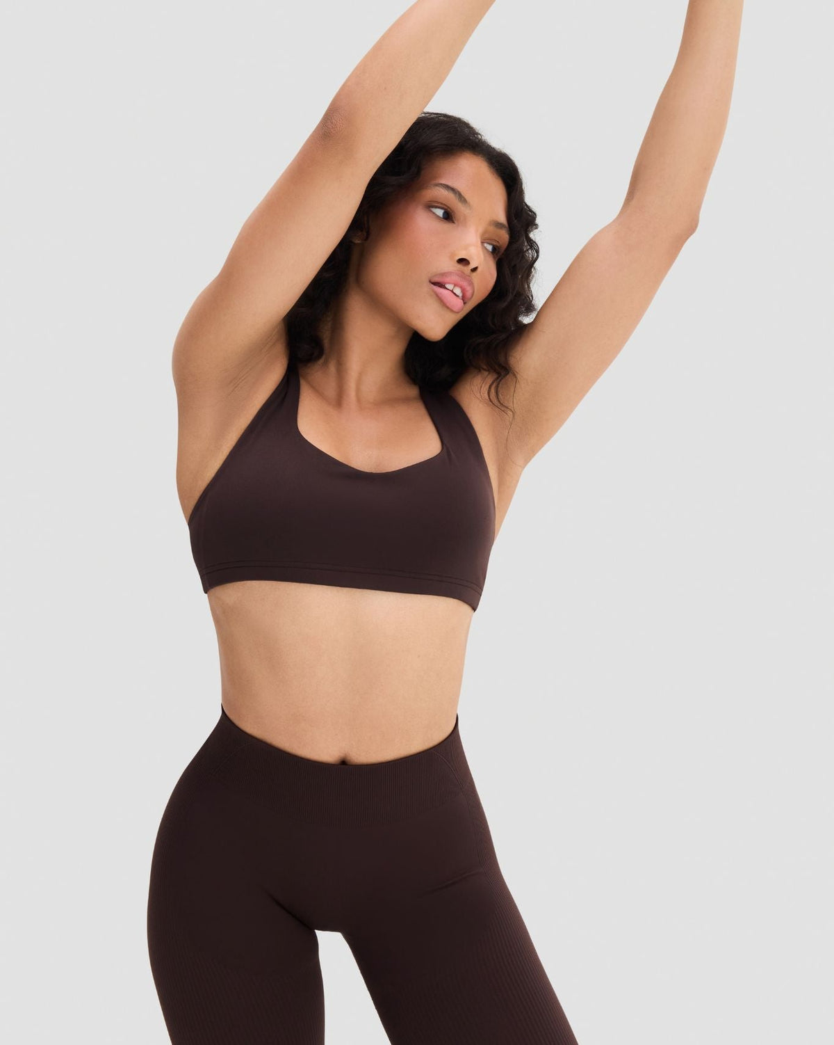 Elevate Sculpting Medium Impact Multiway Bra in Coffee Brown, front view with arms raised, styled with leggings