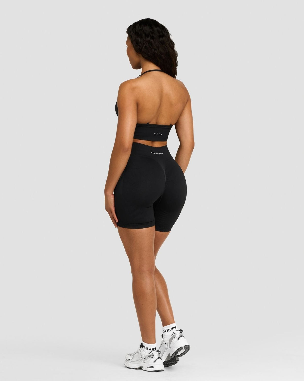 Elevate Sculpting Mid Waist Scrunch Shorts in Night Black, full-length back view over the shoulder