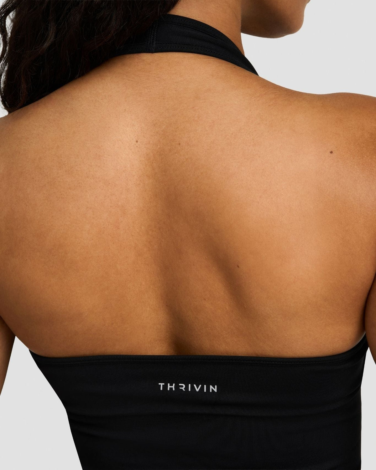 Elevate Sculpting Seamless Halterneck Top in Night Black, back close-up of open back and THRIVIN logo band