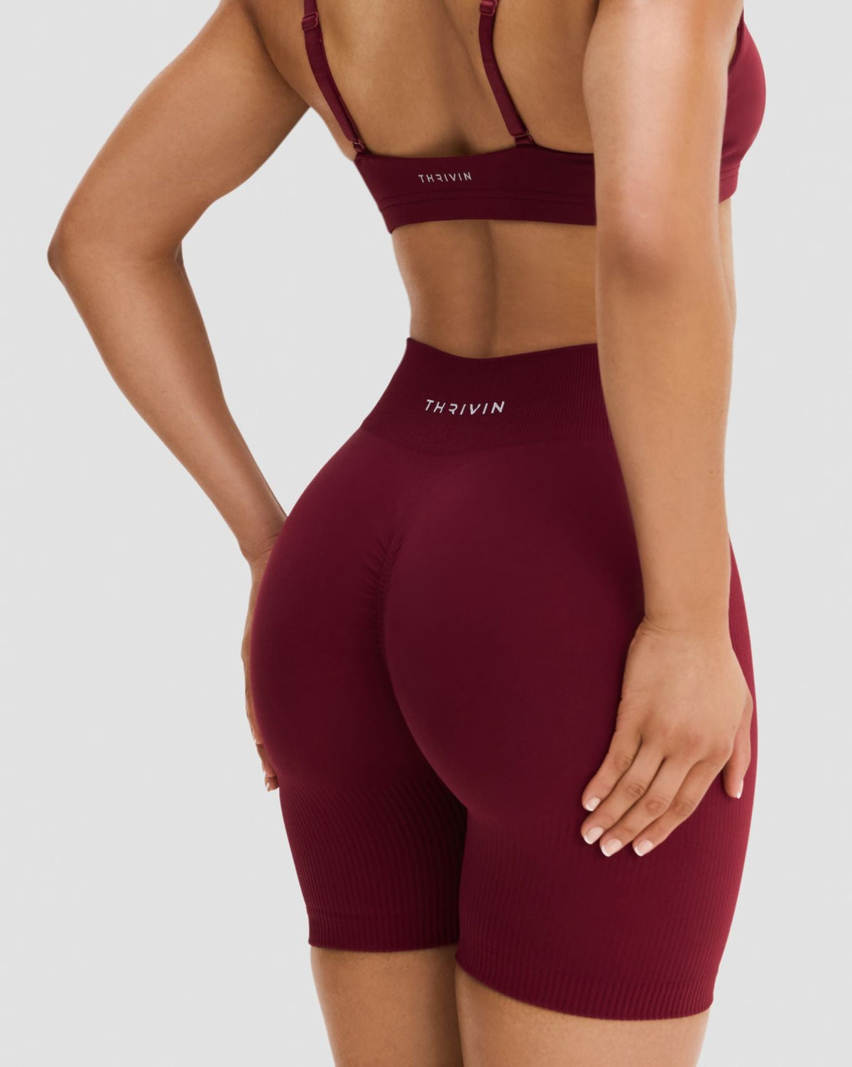 Elevate Sculpting Mid Waist Scrunch Shorts in Fine Wine Red, back close-up of THRIVIN logo, scrunch seam and ribbed leg hem