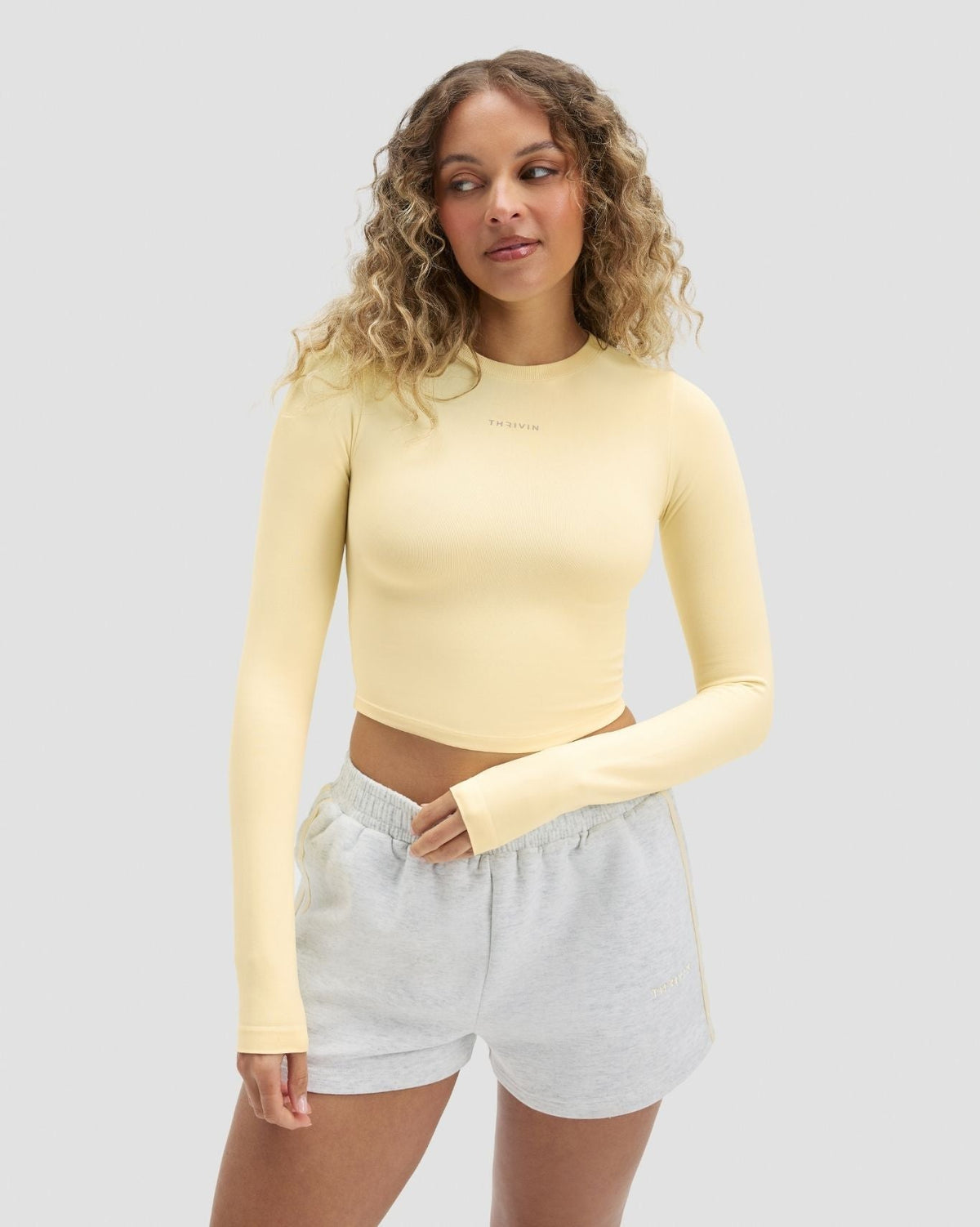 Elevate Compression Long Sleeve Top in Butter Yellow, front three-quarter view with thumbholes