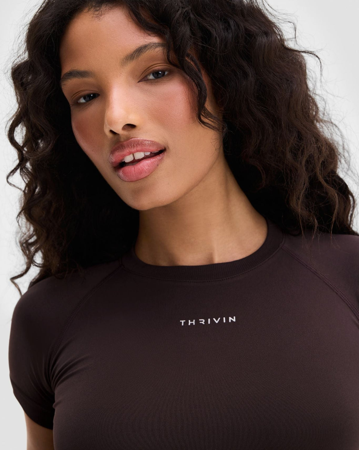 Elevate Compression T-Shirt in Coffee Brown, front close-up of THRIVIN logo, looking over shoulder