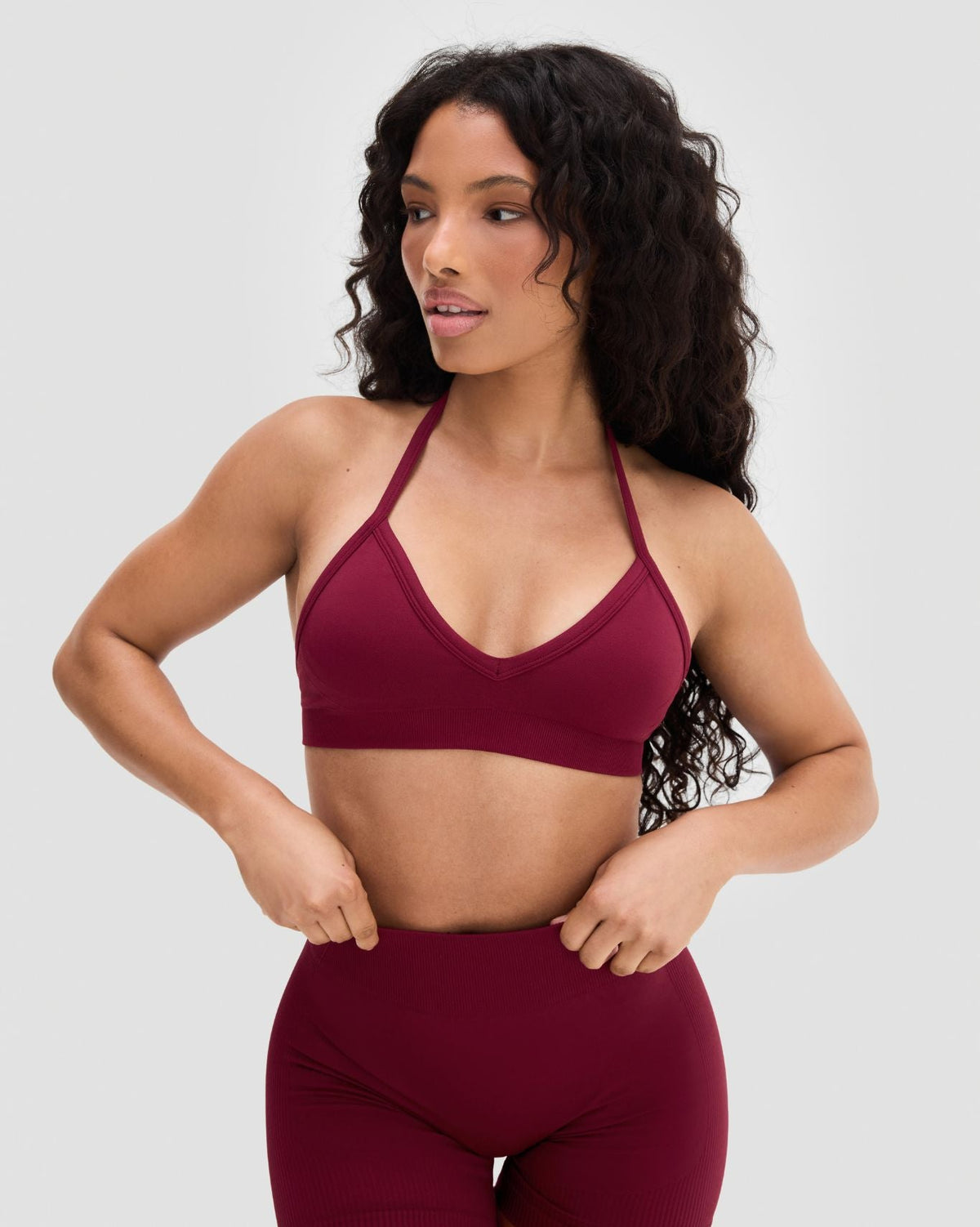 Elevate Sculpting Seamless Adjustable Halter Bra in Fine Wine Red, front view with hands at waist, with matching shorts