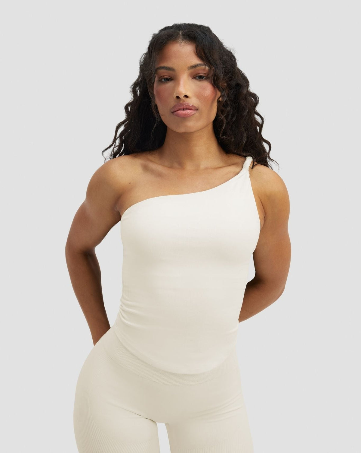 Elevate Sculpting Asymmetric Twist Top in Cream, front view with leggings