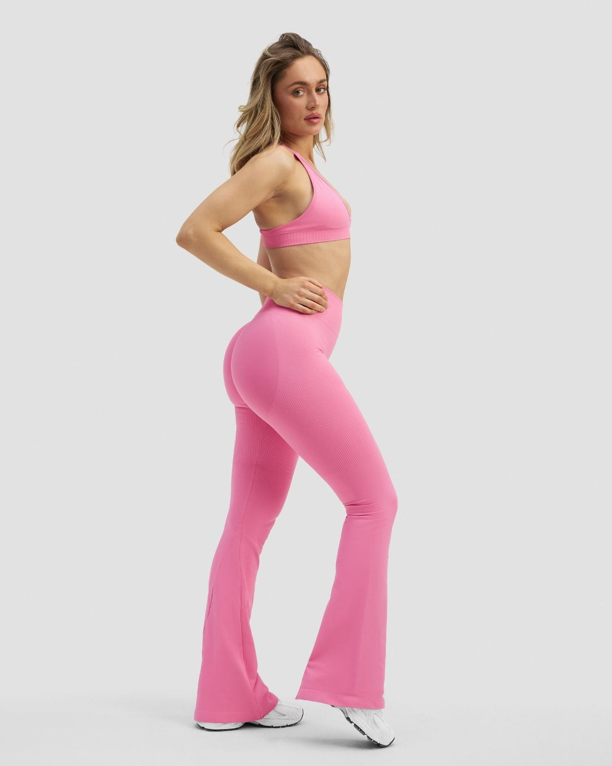 Elevate Sculpting High Waist Flare Leggings in Bubble Pink, three-quarter side view of flared hem with pink bra