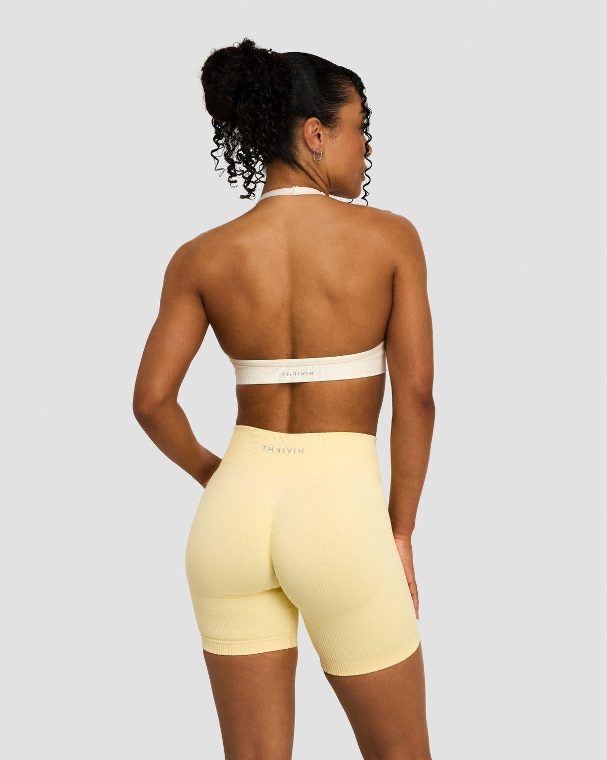 Elevate Sculpting Seamless Adjustable Halter Bra in Cream, back view of open back and halter tie, with yellow shorts