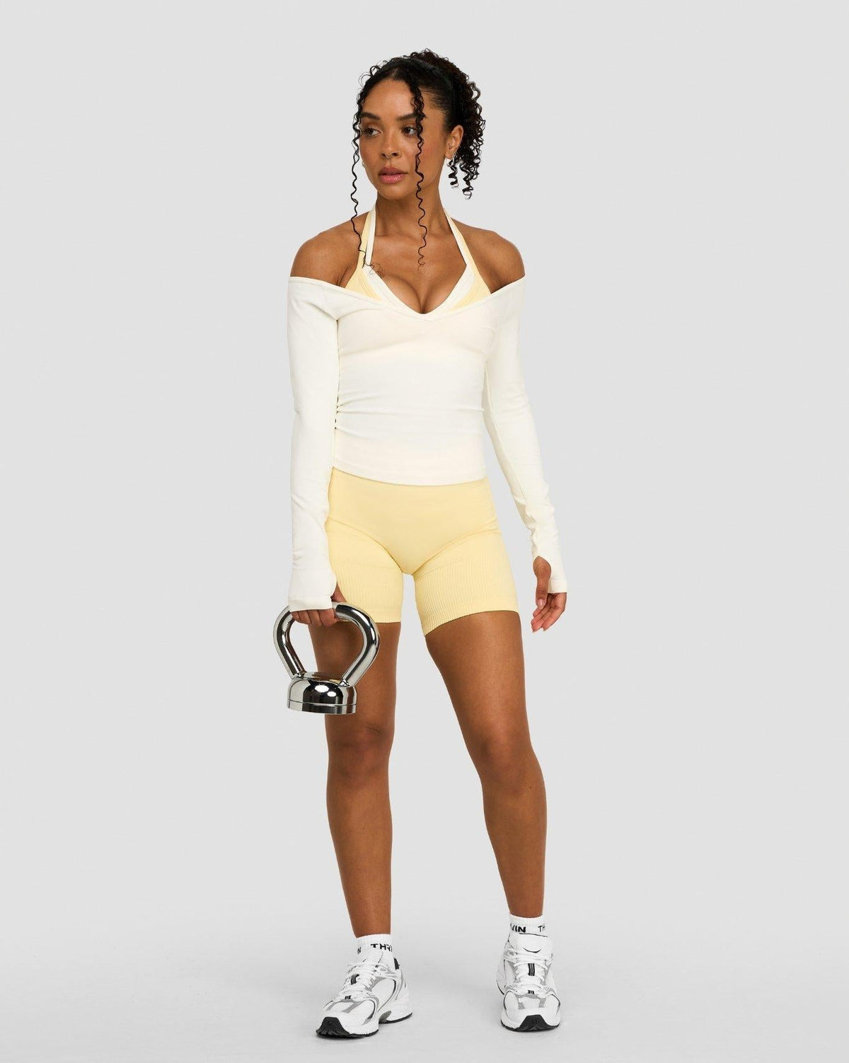 Elevate Sculpting Seamless Adjustable Halter Bra in Cream, front view with matching long sleeve top and yellow shorts