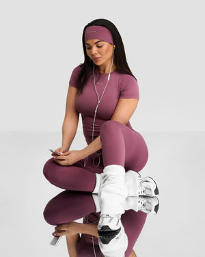 The Essential Collection Chrome Logo Headband in Orchid Mauve, seated view styled with matching T-shirt and leggings