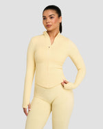 Elevate Compression Long Sleeve Jacket in Butter Yellow, front view with zip, styled with leggings