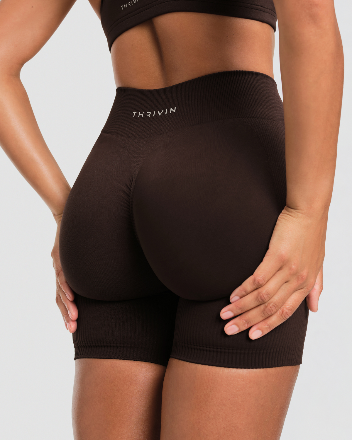 Elevate Sculpting Mid Waist Scrunch Shorts in Coffee Brown, back close-up of scrunch seam, Thrivin logo and ribbed leg hems