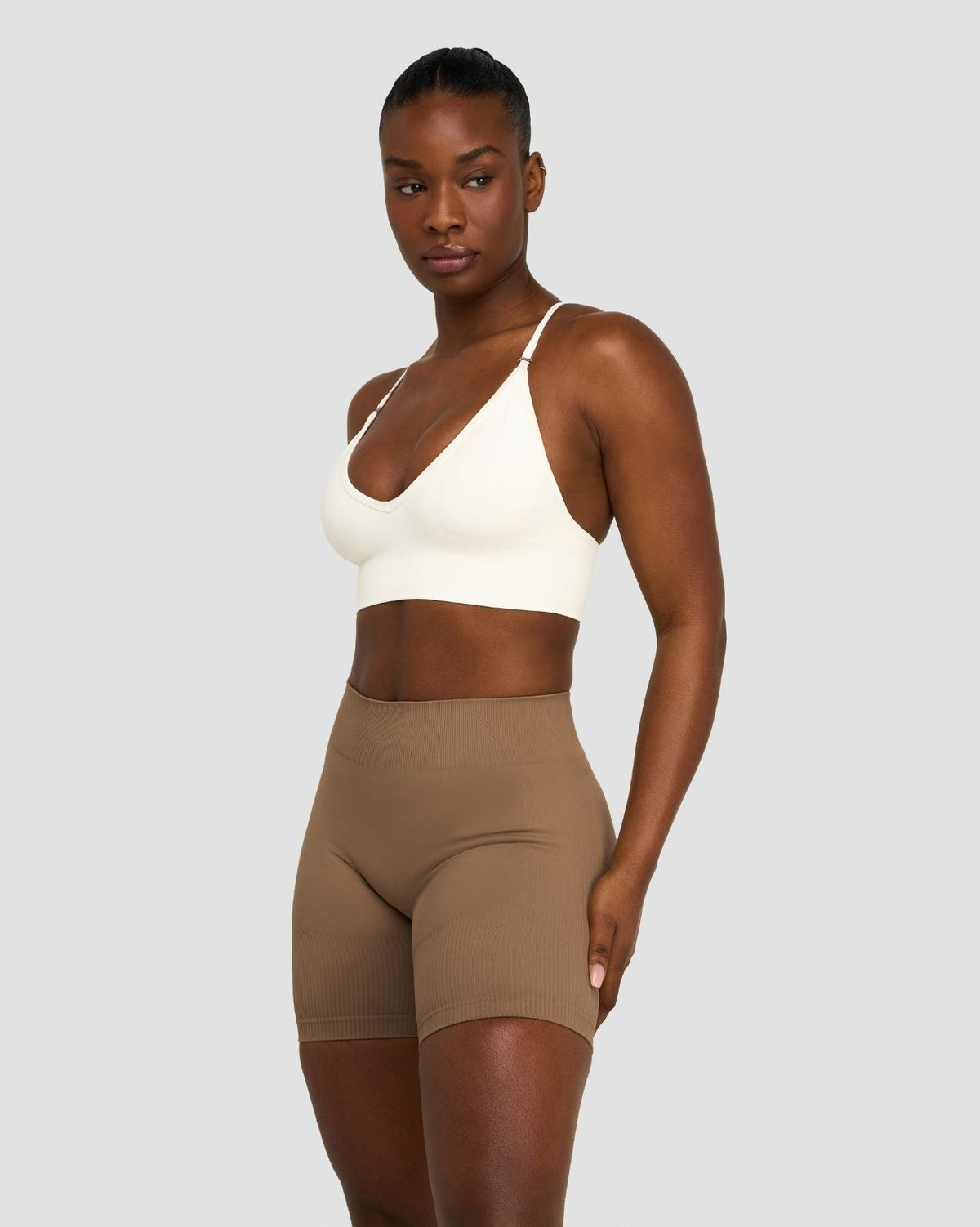 Elevate Multiway Sculpt Seamless Bra in Cream, three-quarter front view of thin straps, styled with shorts