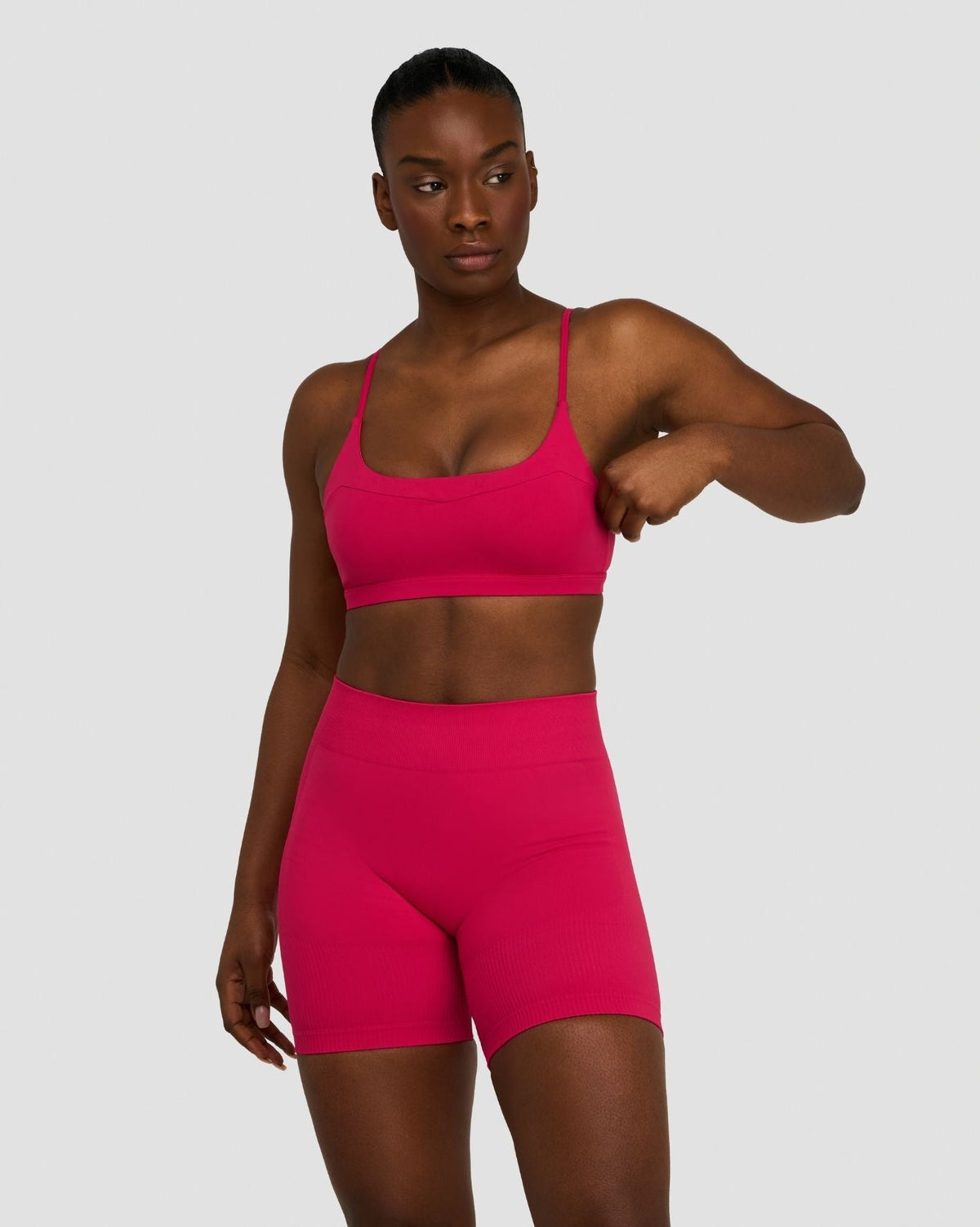 Elevate Sculpting Seamless Scoop Neck Bra in Strawberry, front view, adjusting sleeve, styled with matching shorts