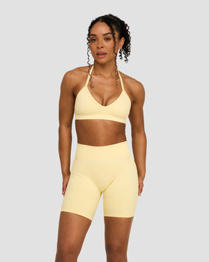 Elevate Sculpting Seamless Adjustable Halter Bra in Butter Yellow, front view with halter ties, styled with matching shorts