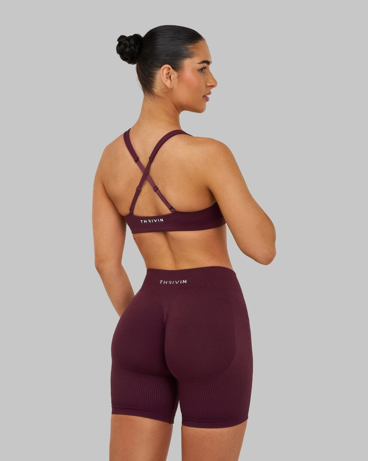 Elevate Sculpting Medium Impact Multiway Bra in Winter Plum Red, back view with crossed straps, styled with shorts