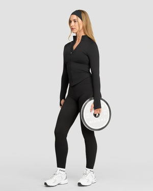 Elevate Compression Long Sleeve Jacket in Charcoal Grey, full front view styled with leggings, holding a disc