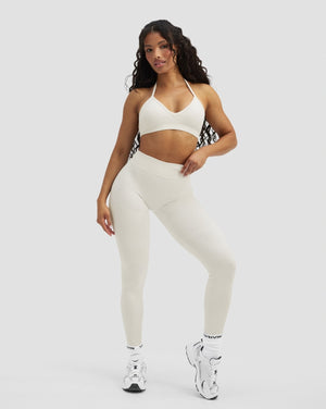 Elevate Sculpting Mid Waist Scrunch Leggings in Cream, front view with hand on hip, styled with cream bra