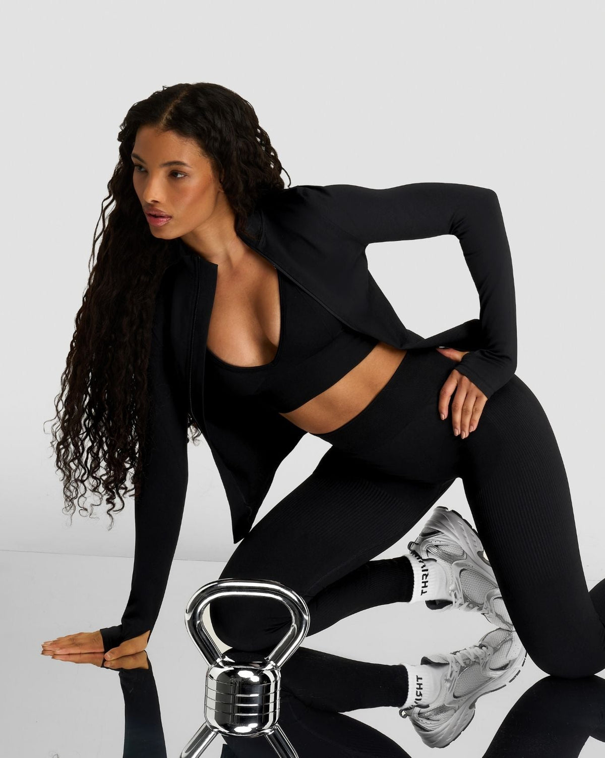 Elevate Compression Long Sleeve Jacket in Night Black, lunging pose beside a kettlebell