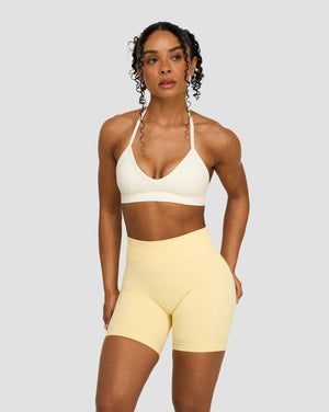 Elevate Sculpting Seamless Adjustable Halter Bra in Cream, front view with halter neck, styled with butter yellow shorts