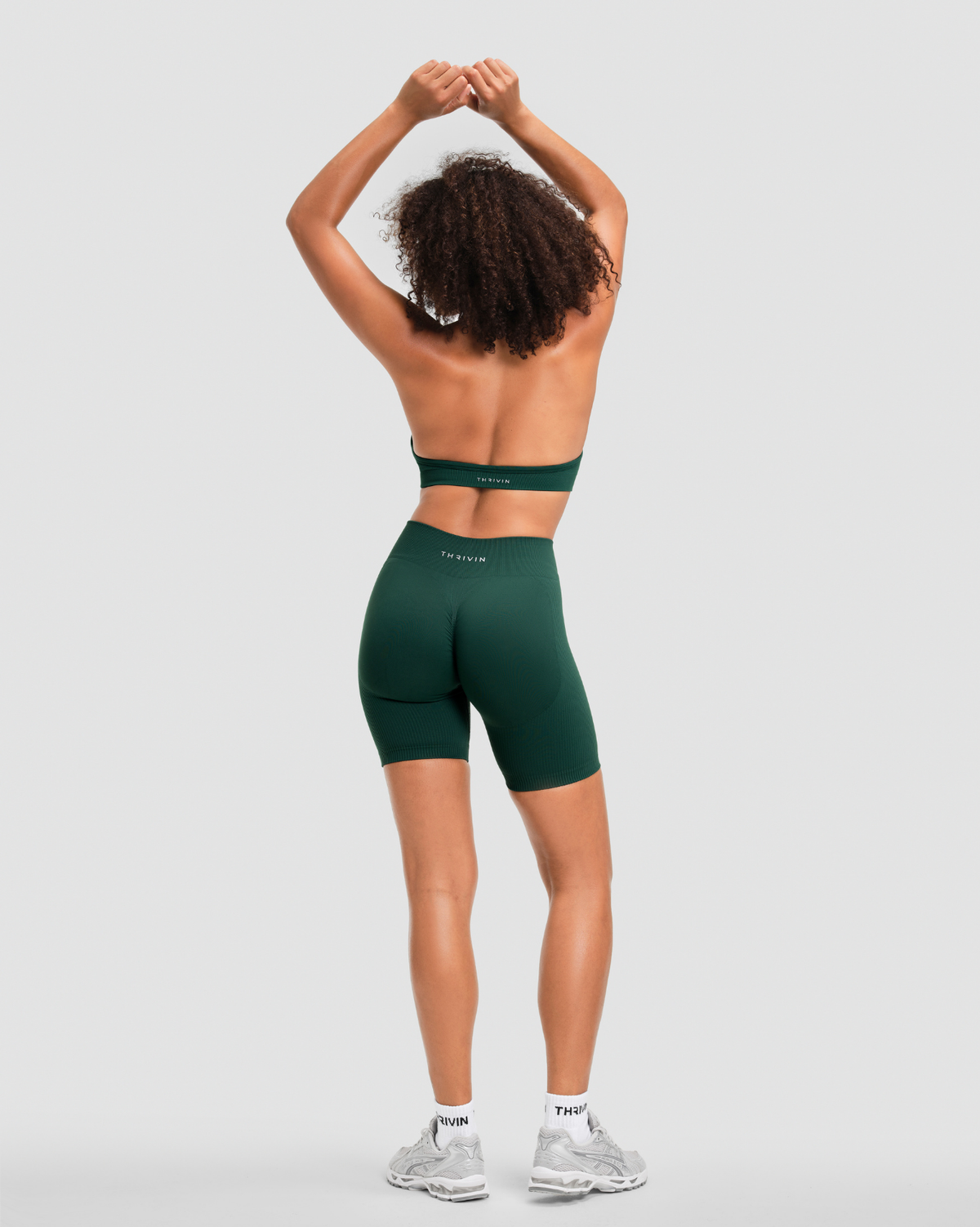 Elevate Sculpting Mid Waist Scrunch Shorts in Pine Green, full-length back view with THRIVIN logo waistband and scrunch seam
